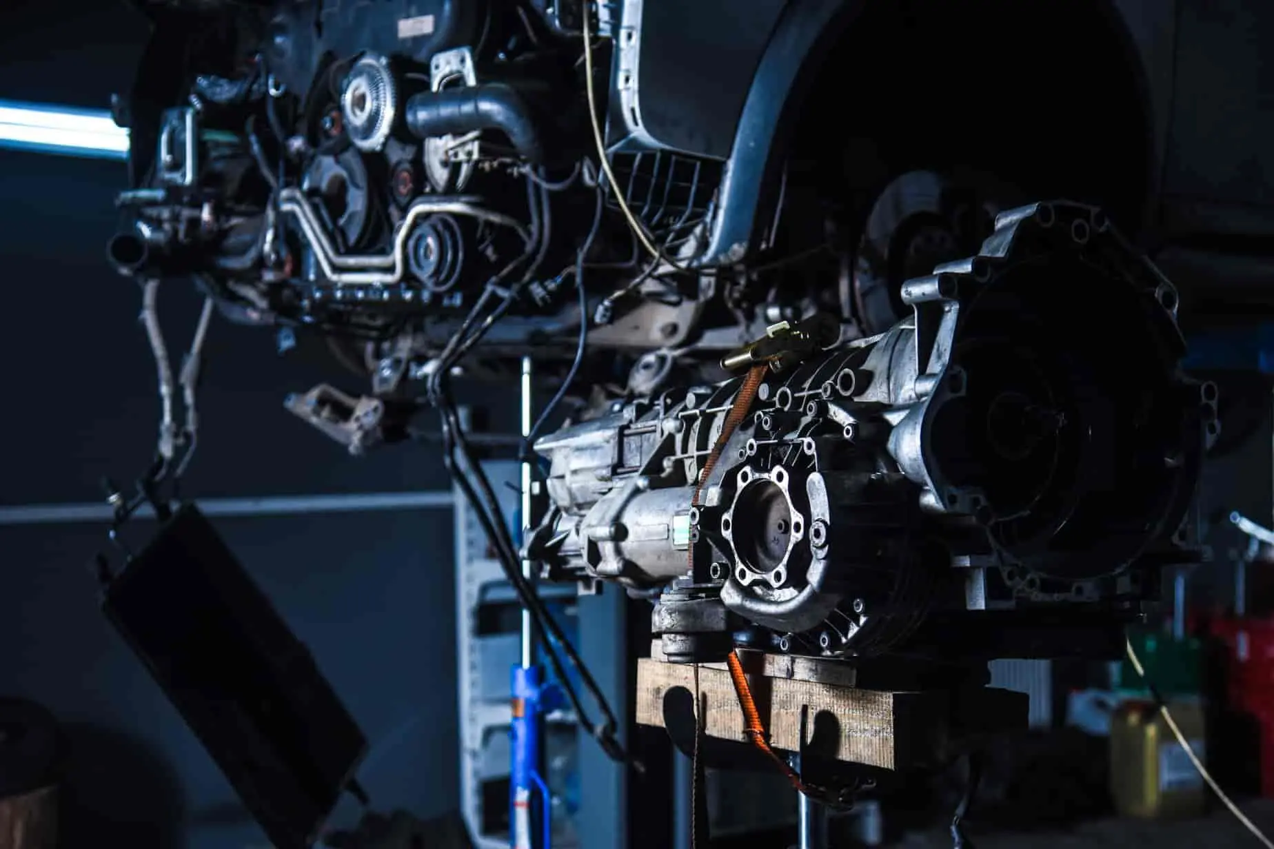 Boîte de vitesses déposée sous véhicule levé, image illustrant une opération de vidange boîte automatique en atelier.