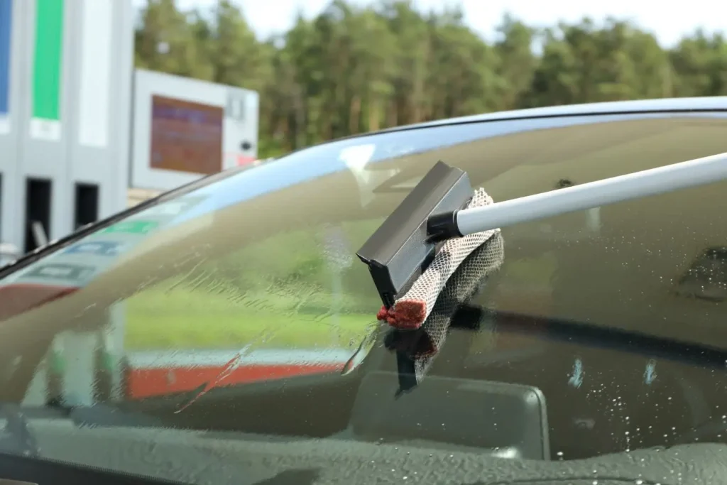 Raclette à double face sur pare-brise humide, image d’un geste pour dégivrer en hiver