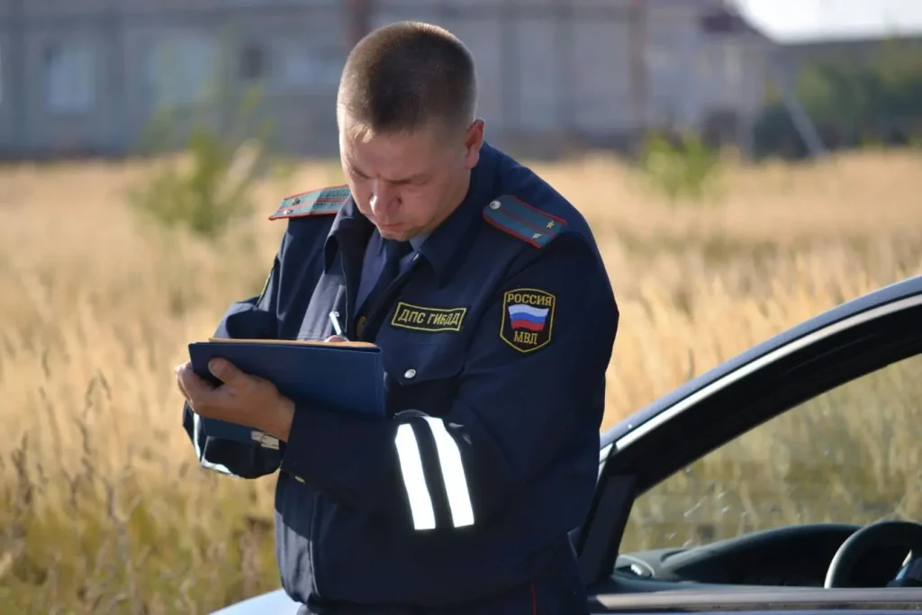 Policier en uniforme rédigeant sur un carnet près d’une voiture, image évoquant le stationnement sur trottoir sanctionné par un contrôle routier.