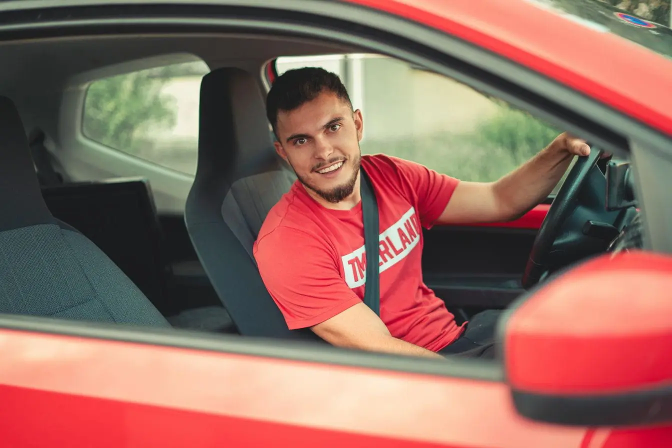 Conducteur en tenue décontractée au volant, image évoquant le permis de conduire international et la conduite transfrontalière.