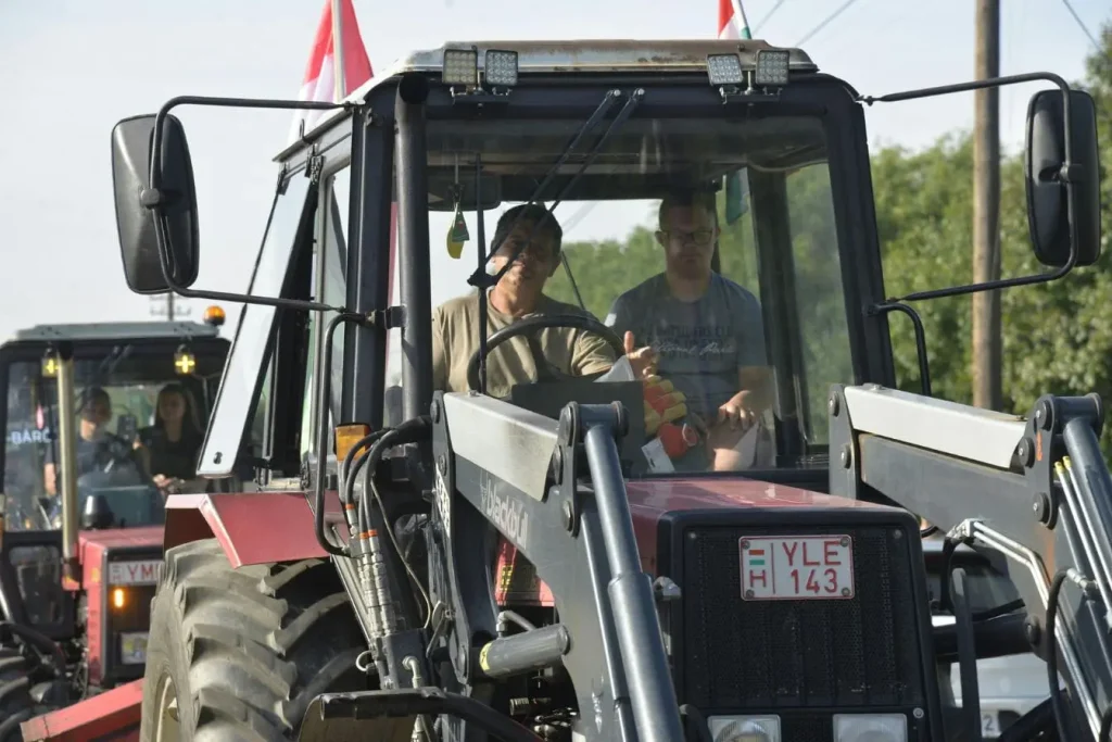 Tracteur rouge avançant sur route avec remorque, image illustrant la nécessité d’un permis spécifique pour tracter une remorque en toute légalité.