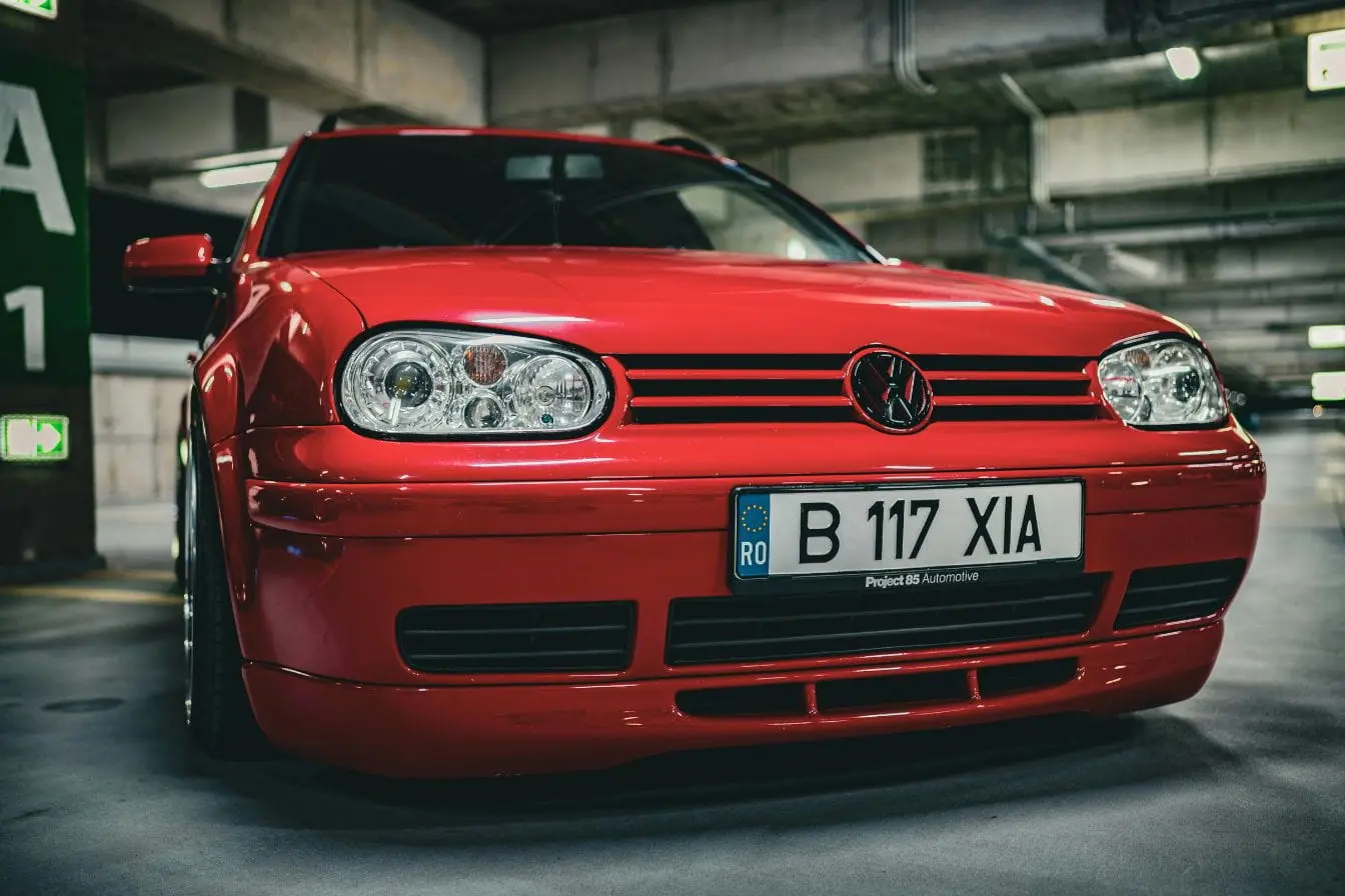 Voiture rouge stationnée en parking, image illustrant le calcul du cheval fiscal et du coût réel d’une carte grise pour immatriculation.