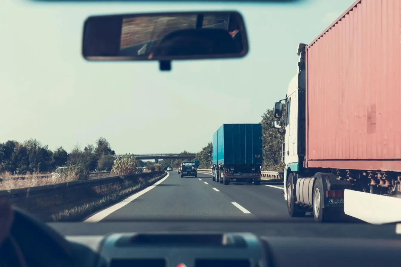 Vue depuis un véhicule sur autoroute avec camions visibles, image évoquant l’importance de respecter la distance de sécurité pour éviter collisions.