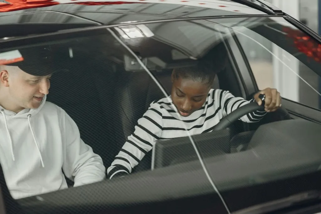 Deux personnes assises à l’avant d’une voiture, image illustrant la conduite accompagnée et l’apprentissage progressif des règles de sécurité routière.