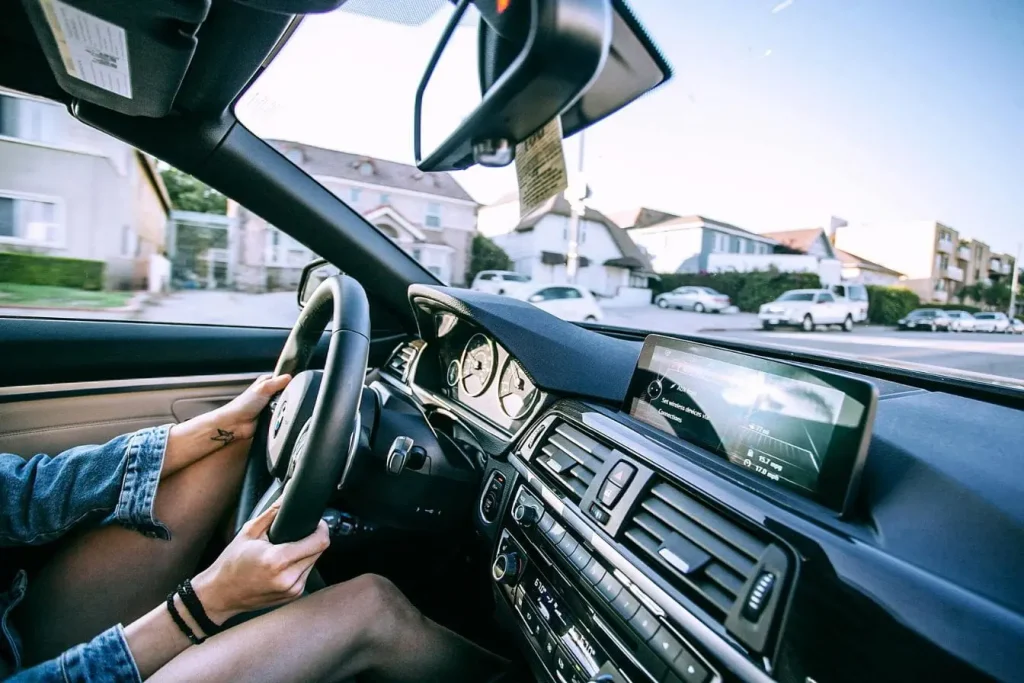 Conducteur tenant le volant avec vue sur tableau de bord, image illustrant la transition du permis auto au manuel et l’apprentissage pratique.