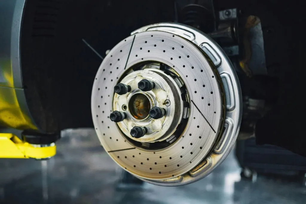Disque métallique ventilé avec trous visibles, symbole du remplacement des plaquettes de frein lors d’un entretien automobile.