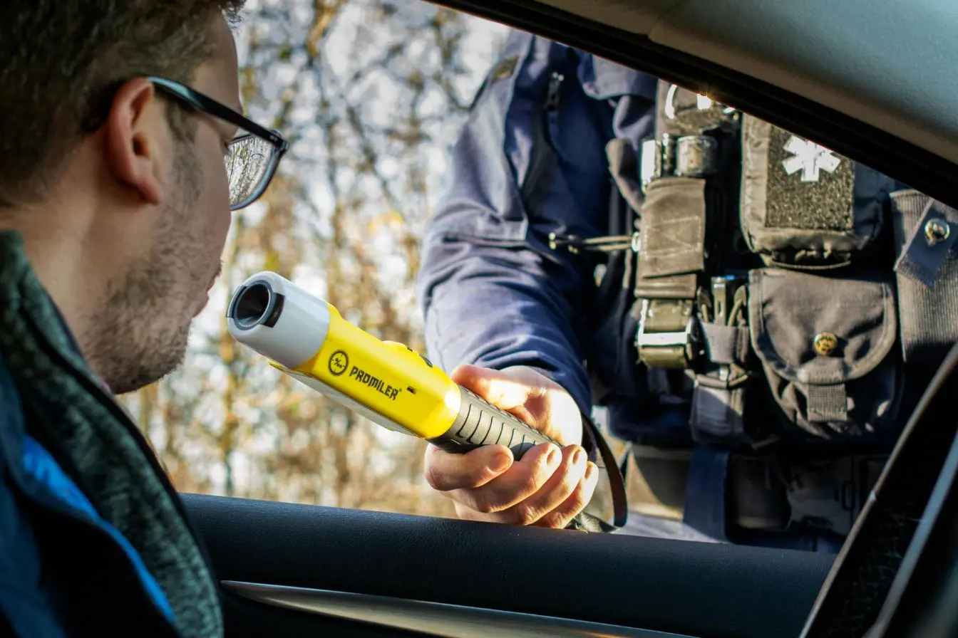 éthylotest Policier tenant éthylotest vers conducteur, image illustrant la lutte contre l’alcool au volant.