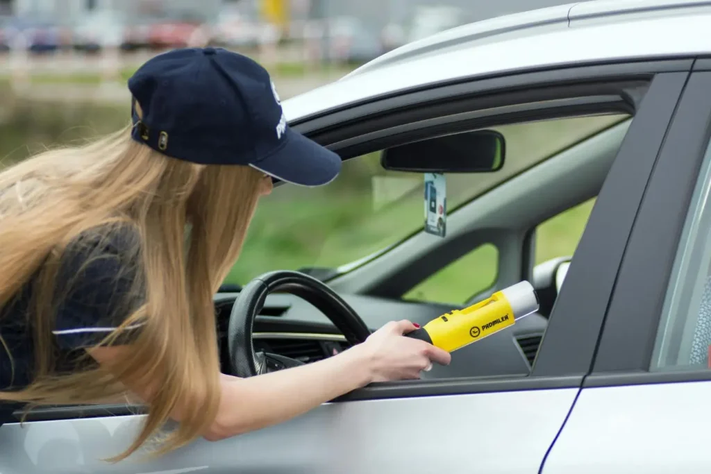 Policier en uniforme utilisant appareil jaune pour test d’alcoolémie auprès d’un conducteur, image illustrant la prévention contre l’alcool au volant.