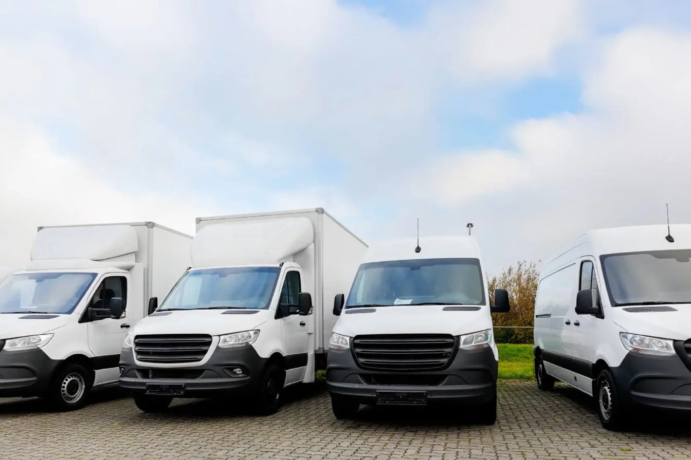 Flotte de camions et fourgons blancs stationnés représentant la procédure administrative pour duplicata de carte grise perdue