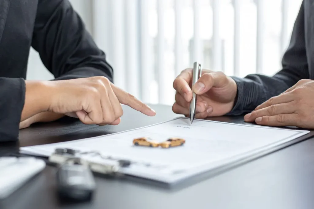 Gros plan sur signature de contrat automobile avec clés posées, illustrant la conformité légale grâce au certificat de non‑gage.