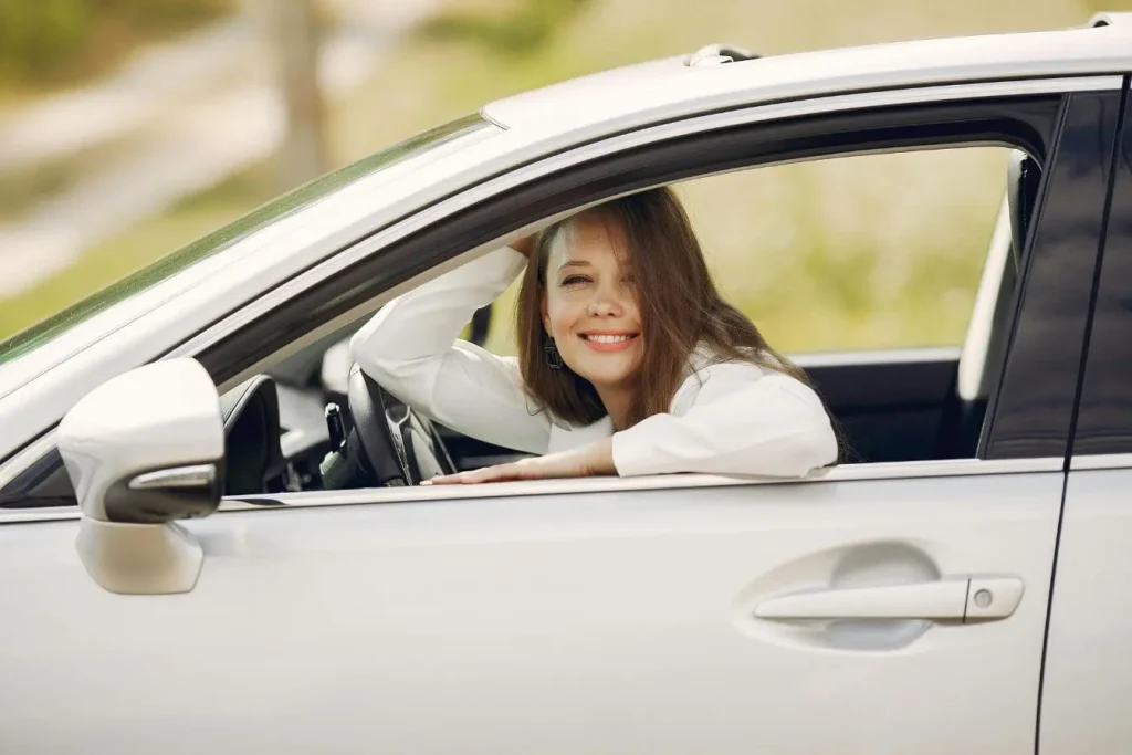 Personne appuyée à la fenêtre ouverte, symbole du passage du permis auto au manuel et de la maîtrise progressive.