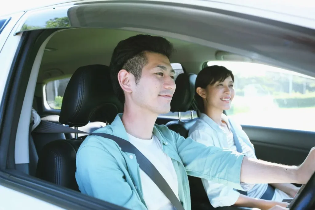 Deux personnes assises à l’avant d’une voiture moderne, image illustrant le permis de conduire international et la mobilité transfrontalière.