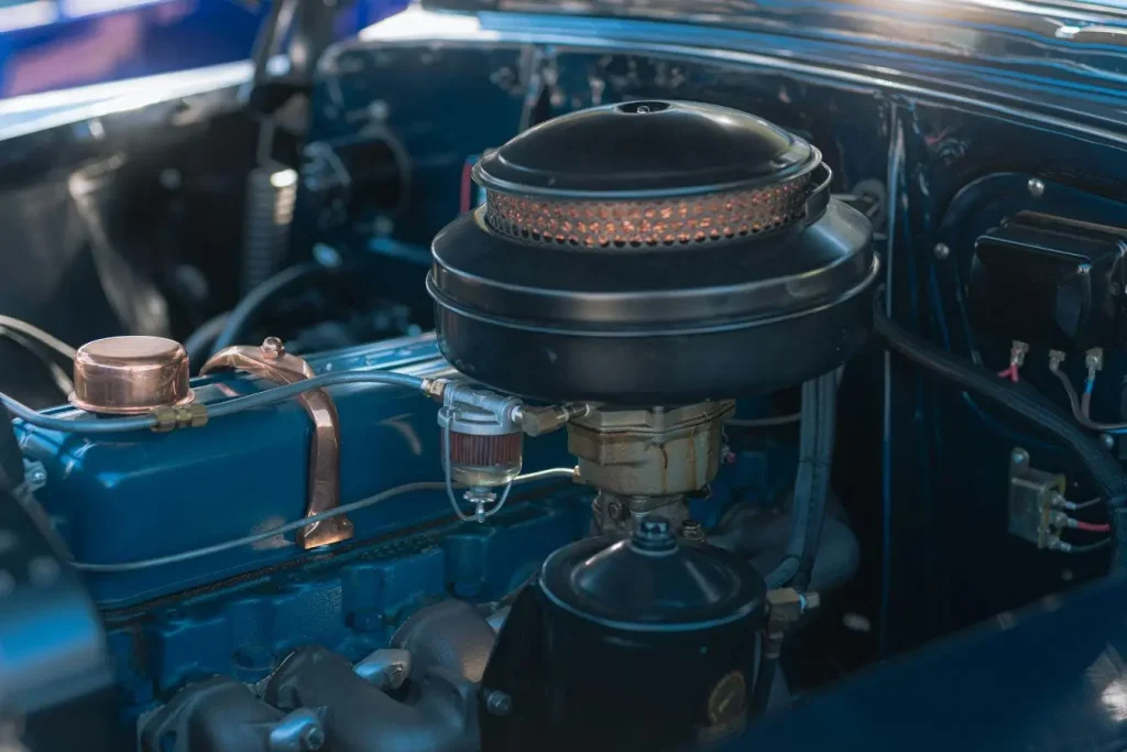 Gros plan sur moteur bleu avec filtre rond et durites, image évoquant les signes de défaillance possibles d’une pompe à eau.