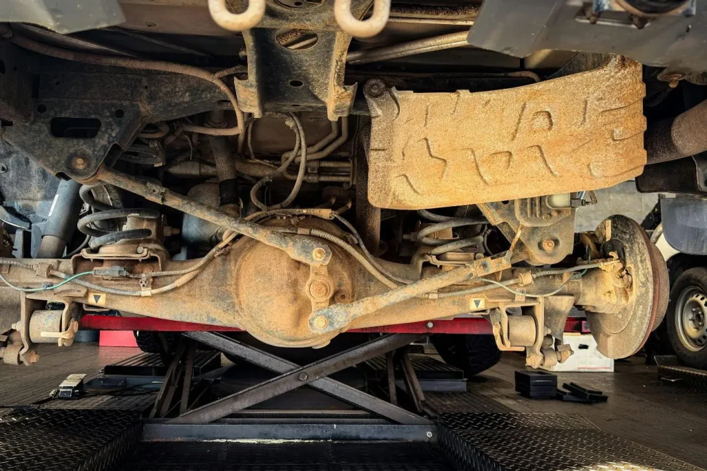 Vue de dessous d’un véhicule montrant suspension et cardan usé, image illustrant un cardan qui claque.