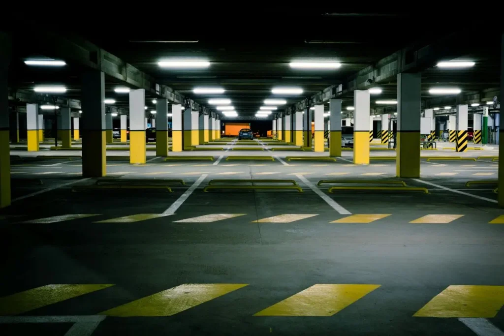 Parking souterrain éclairé reflétant les interrogations sur les risques réels liés à la recharge de voitures électriques en sous-sol.