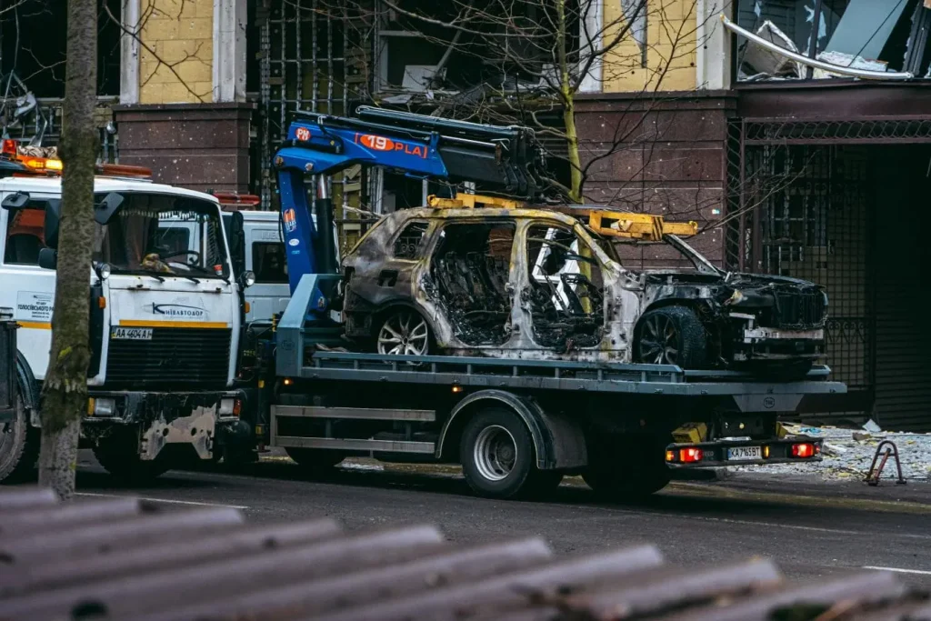 Dépanneuse transportant une voiture brûlée illustrant la nécessité de suivre les démarches légales pour se débarrasser d’un véhicule épave.