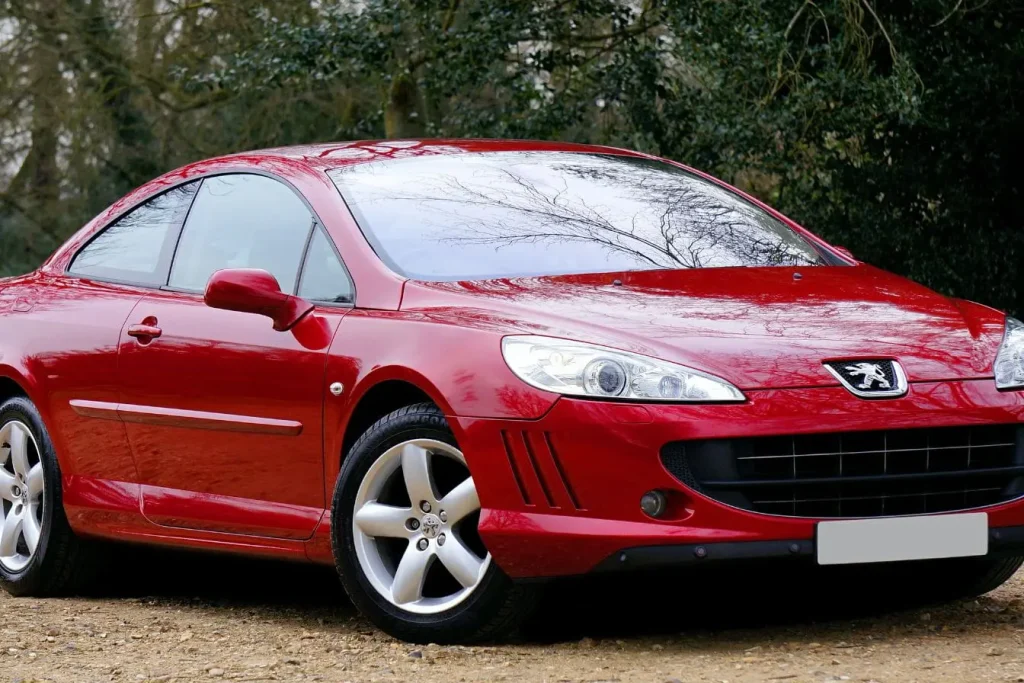 Peugeot rouge garée sur gravier reflétant l’importance du bonus écologique 2026 pour encourager l’achat de véhicules plus respectueux de l’environnement.