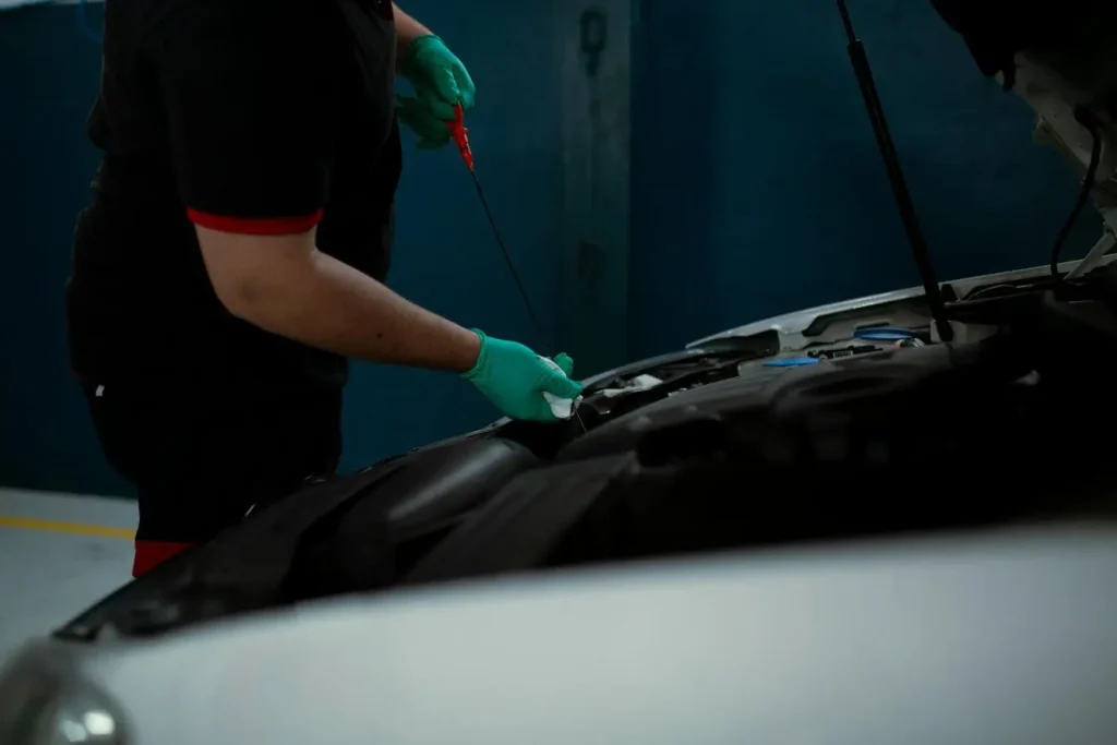 Gros plan moteur ouvert, une personne retire et essuie une jauge, image pratique pour comprendre la vérification et l’appoint du liquide de frein.
