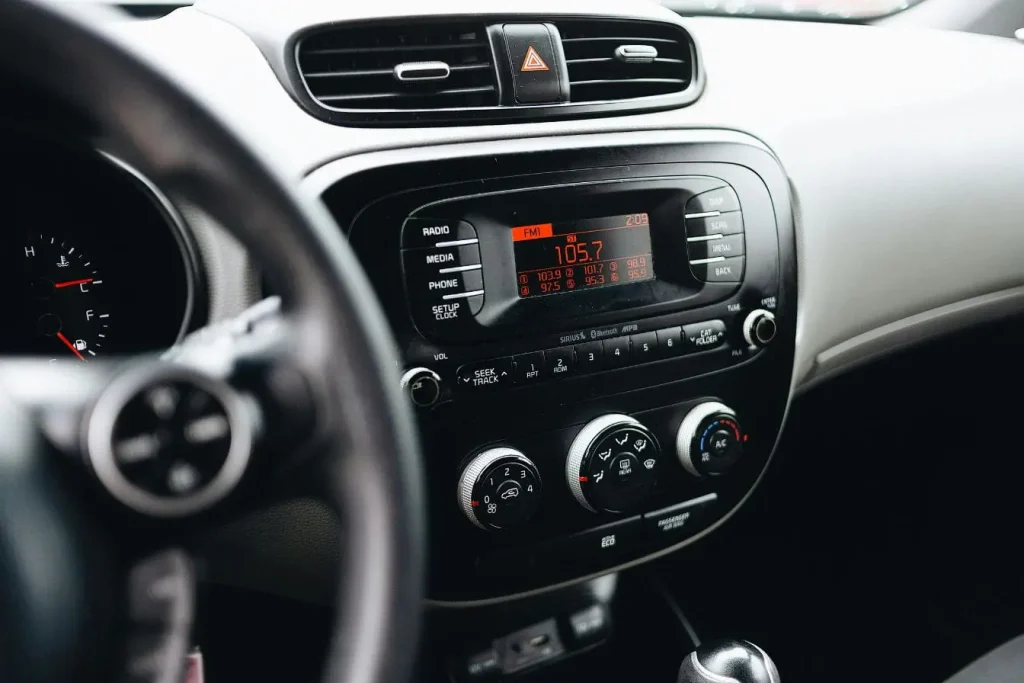 Tableau de bord avec affichage radio et commandes de ventilation, illustrant l’entretien de la climatisation de voiture pour assurer confort et efficacité.