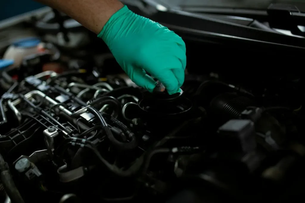 Main gantée en vert manipulant moteur, image illustrant le remplacement d’un injecteur diesel pour assurer performance et fiabilité du véhicule.