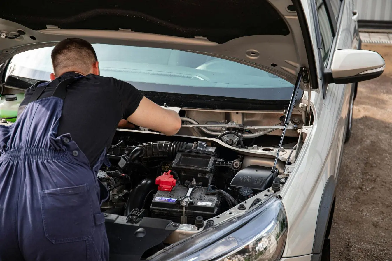 remplacement d’un injecteur Mécanicien en bleu de travail penché sous capot ouvert, image illustrant le remplacement d’un injecteur diesel pour assurer bon fonctionnement moteur.
