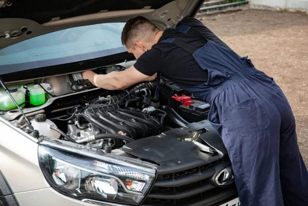 Mécanicien en bleu de travail penché sous capot, image illustrant la réparation d’un injecteur diesel encrassé.