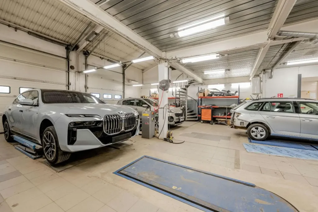 Garage organisé avec plusieurs véhicules en réparation, symbole des pratiques liées aux frais d’entretien électrique et thermique.