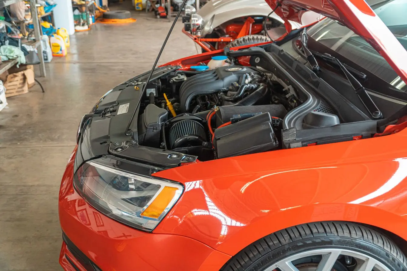 Capot rouge ouvert dévoile moteur avec câbles et filtres, image illustrant un kit de conversion E85 et la question de fiabilité moteur.