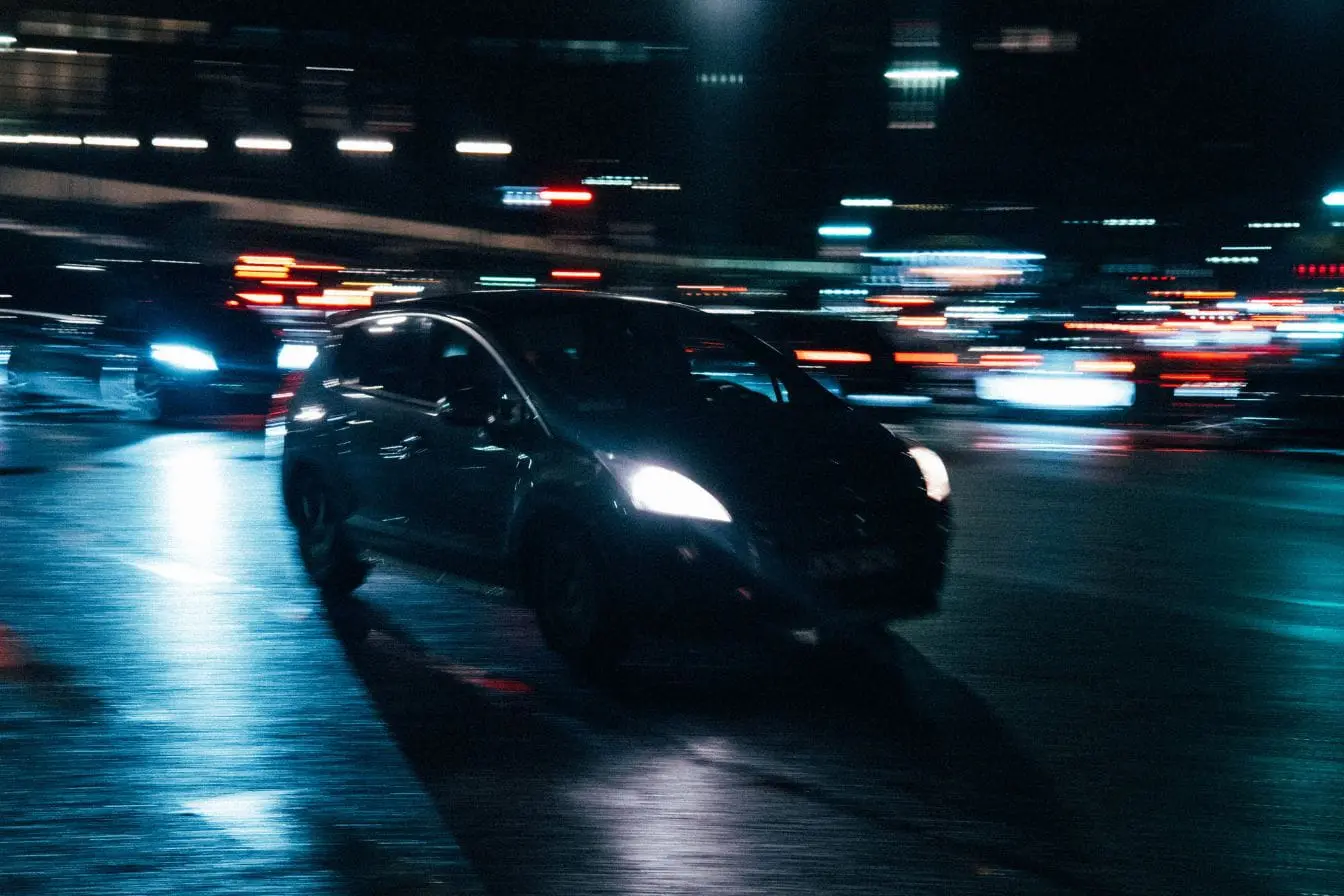 Voiture roulant de nuit sur route éclairée, image qui illustre la vigilance nécessaire pour respecter les règles de dépassement en France.