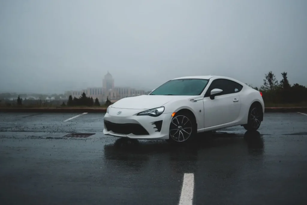 Voiture sportive blanche garée devant bâtiment brumeux, symbole d’un véhicule concerné par les avis sur kit E85.