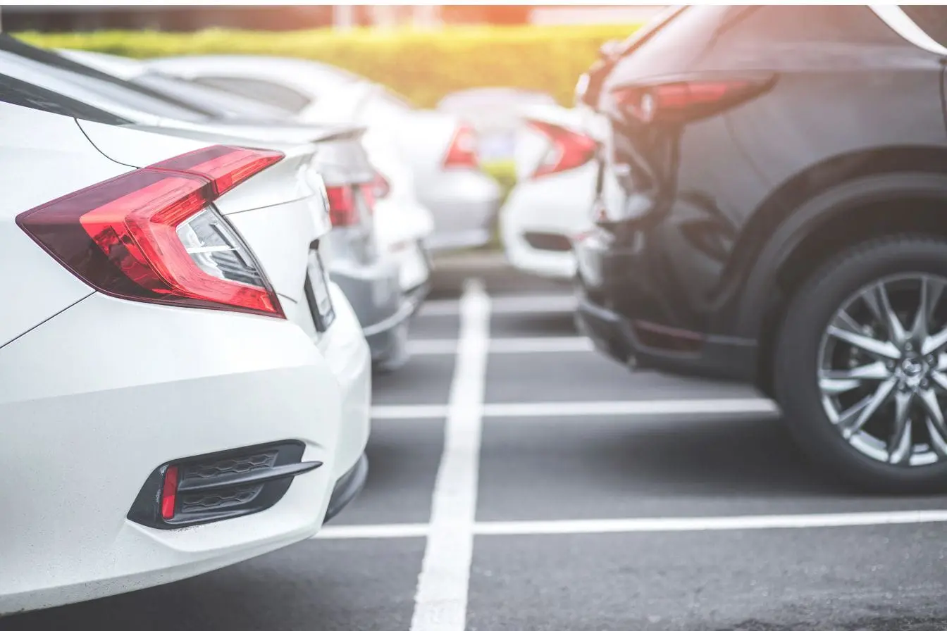 Voitures alignées sur parking en pente douce, image qui illustre la question de stationner en côte sans utiliser le frein à main.