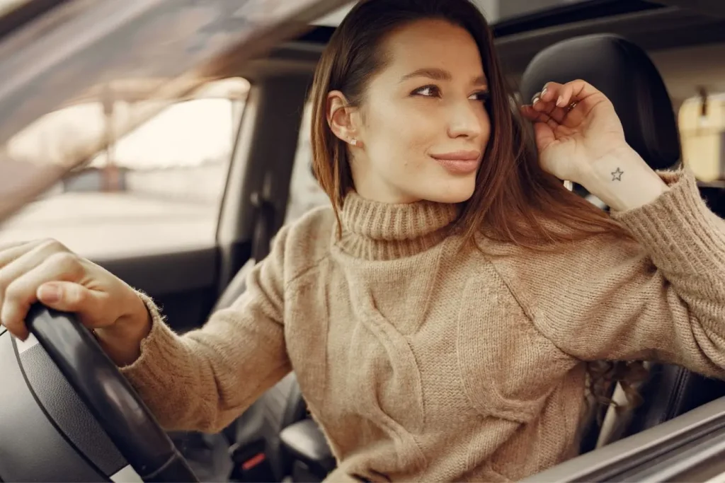 Conductrice assise au volant avec main levée, image qui illustre la responsabilité liée au capital points du permis de conduire.