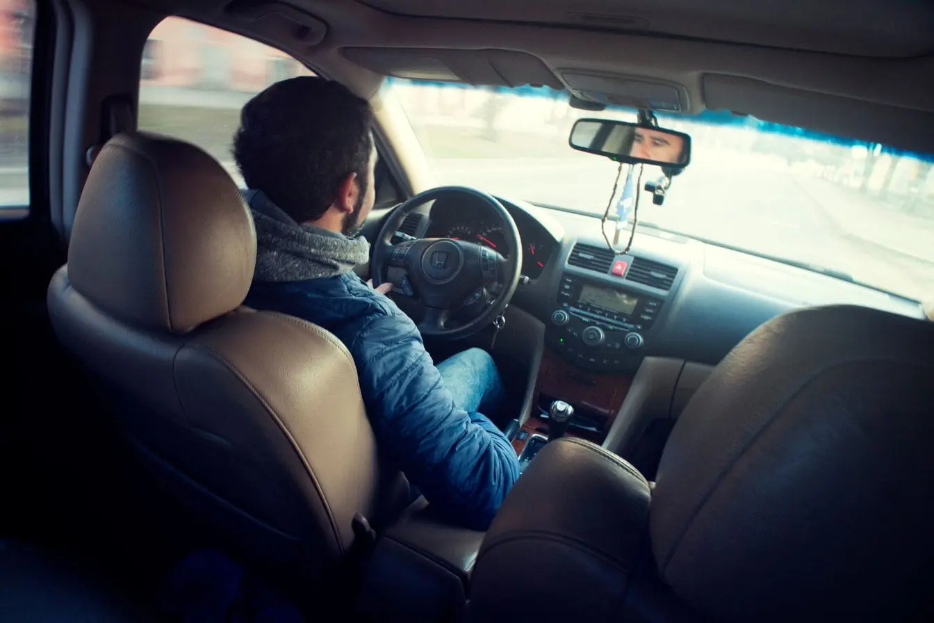 Vue intérieure d’une voiture Conducteur tient volant dans habitacle beige, image illustrant la conduite au Maroc avec permis français et respect des règles local