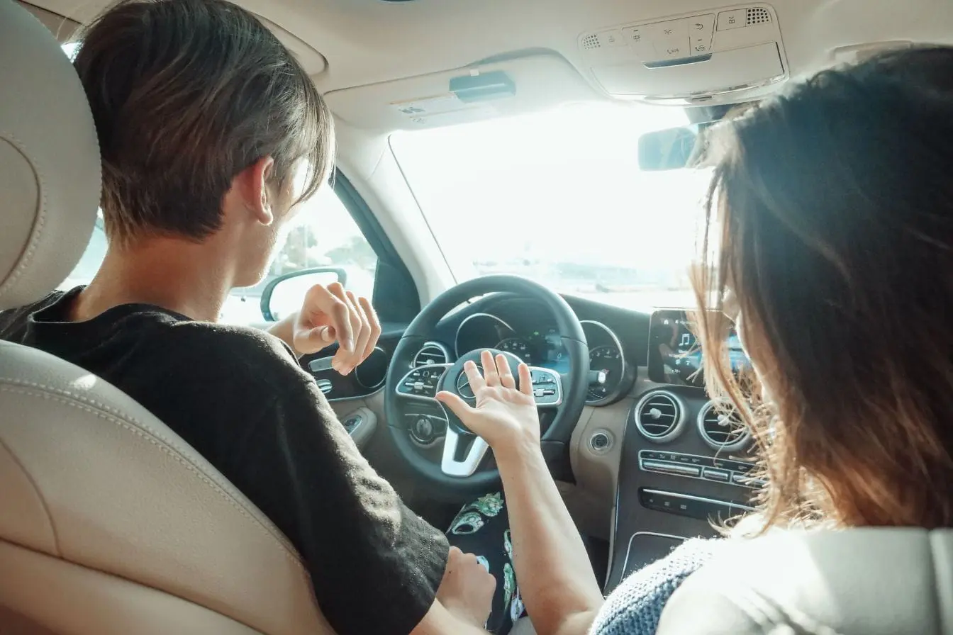 Deux personnes assises à l’avant d’une voiture discutent, image qui illustre l’apprentissage et le coût d’une formation de moniteur auto-école.