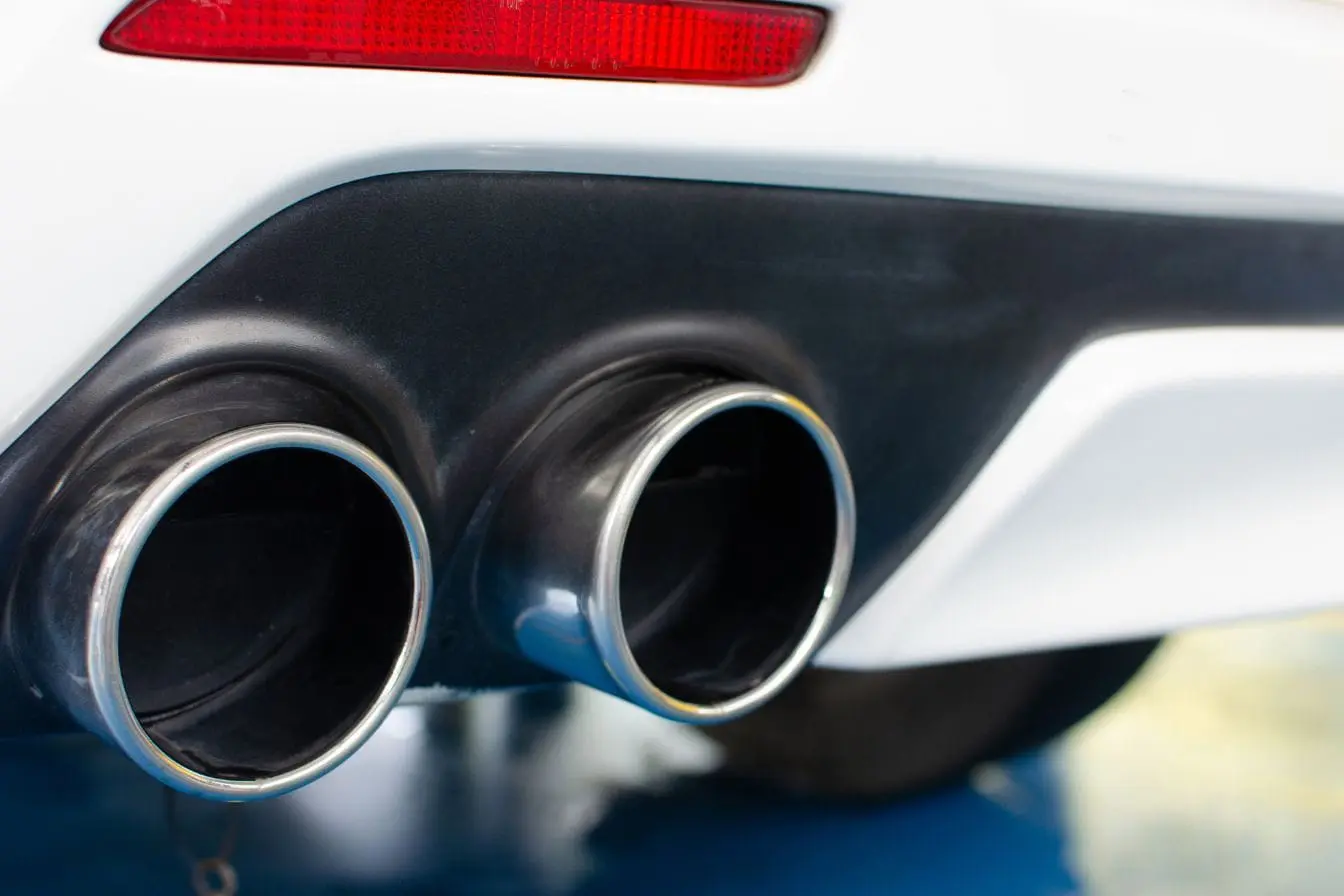 Vue arrière d’une voiture blanche avec double échappement poli, image qui illustre la réglementation encadrant la modification du pot d’échappement.