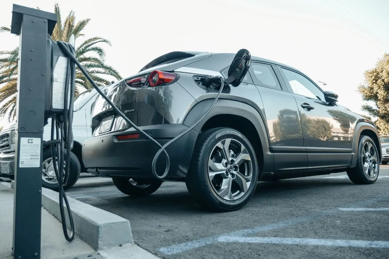 Voiture électrique grise branchée à une borne, image qui illustre la recharge et rappelle le rôle du freinage régénératif dans la récupération d’énergie.