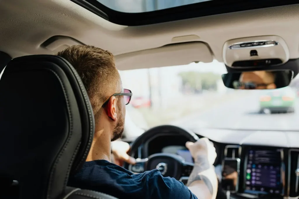 Conducteur vu depuis l’arrière tenant fermement le volant, image qui illustre la réactivité et la sécurité du freinage d’urgence automatique.