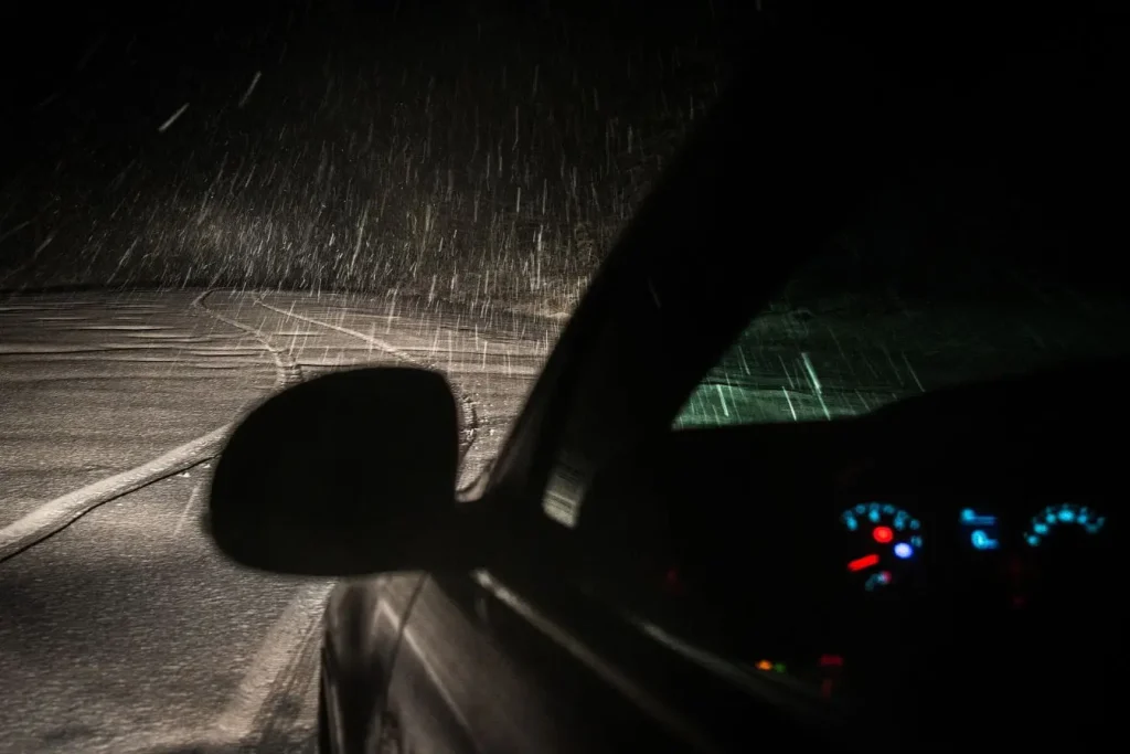 Vue nocturne depuis l’habitacle avec route enneigée éclairée par les phares, image qui illustre l’importance du système de surveillance des angles morts.