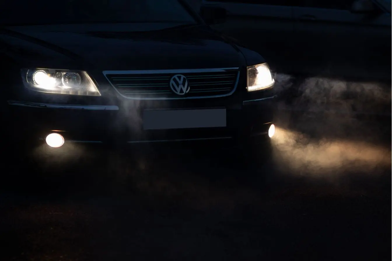 conduire dans le brouillard Voiture noire avançant phares allumés dans la brume, image qui illustre la prudence nécessaire pour conduire dans le brouillard.