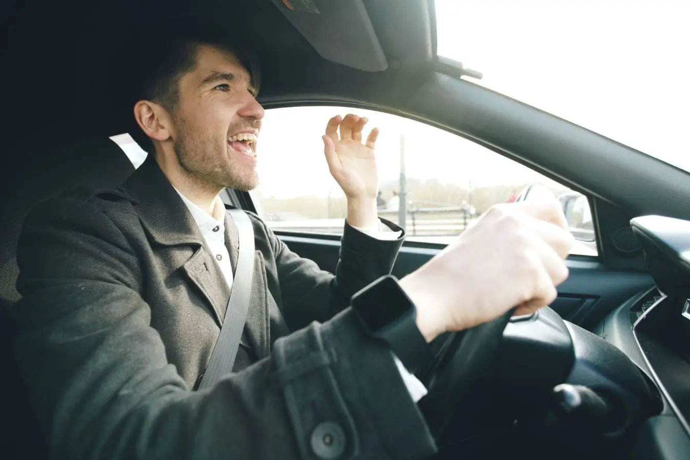 road rage Gros plan sur conducteur en manteau sombre, image claire d’un geste pouvant évoquer le road rage.