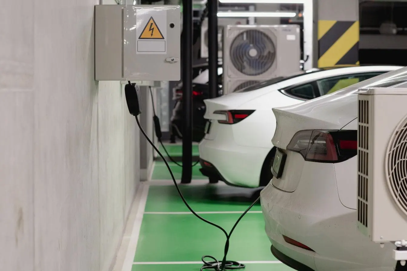 voiture électrique Deux voitures électriques garées côte à côte, l’une branchée à une borne murale, image qui illustre la dégradation progressive des batteries au fil du temps.