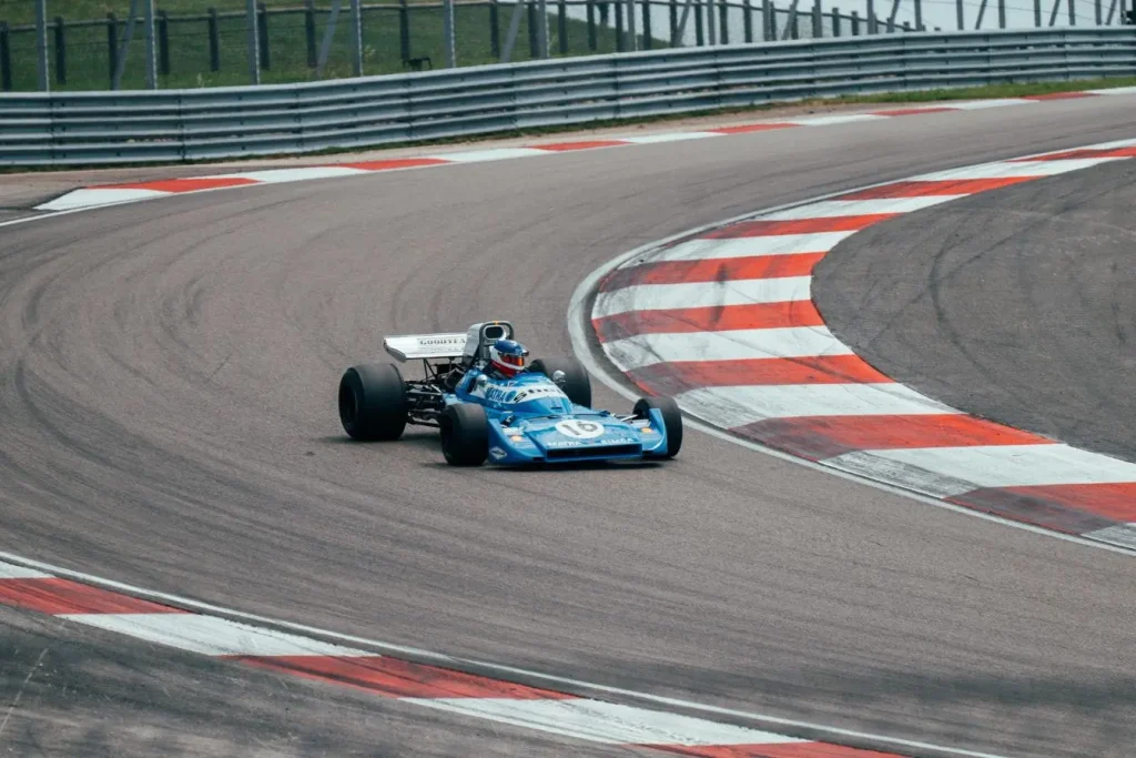 Voiture de course bleue vintage numéro 16 en action sur circuit, reflet des origines et grandes étapes de l’histoire de la Formule 1.
