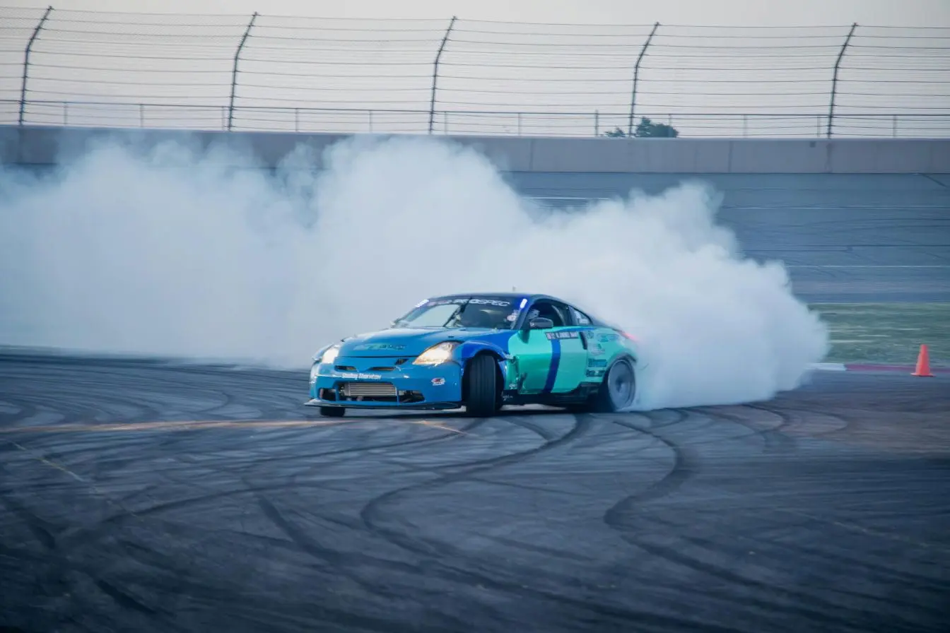 Voiture sportive Voiture sportive bleue et turquoise glissant en travers sur piste, reflet de la maîtrise et de la puissance du drift automobile.