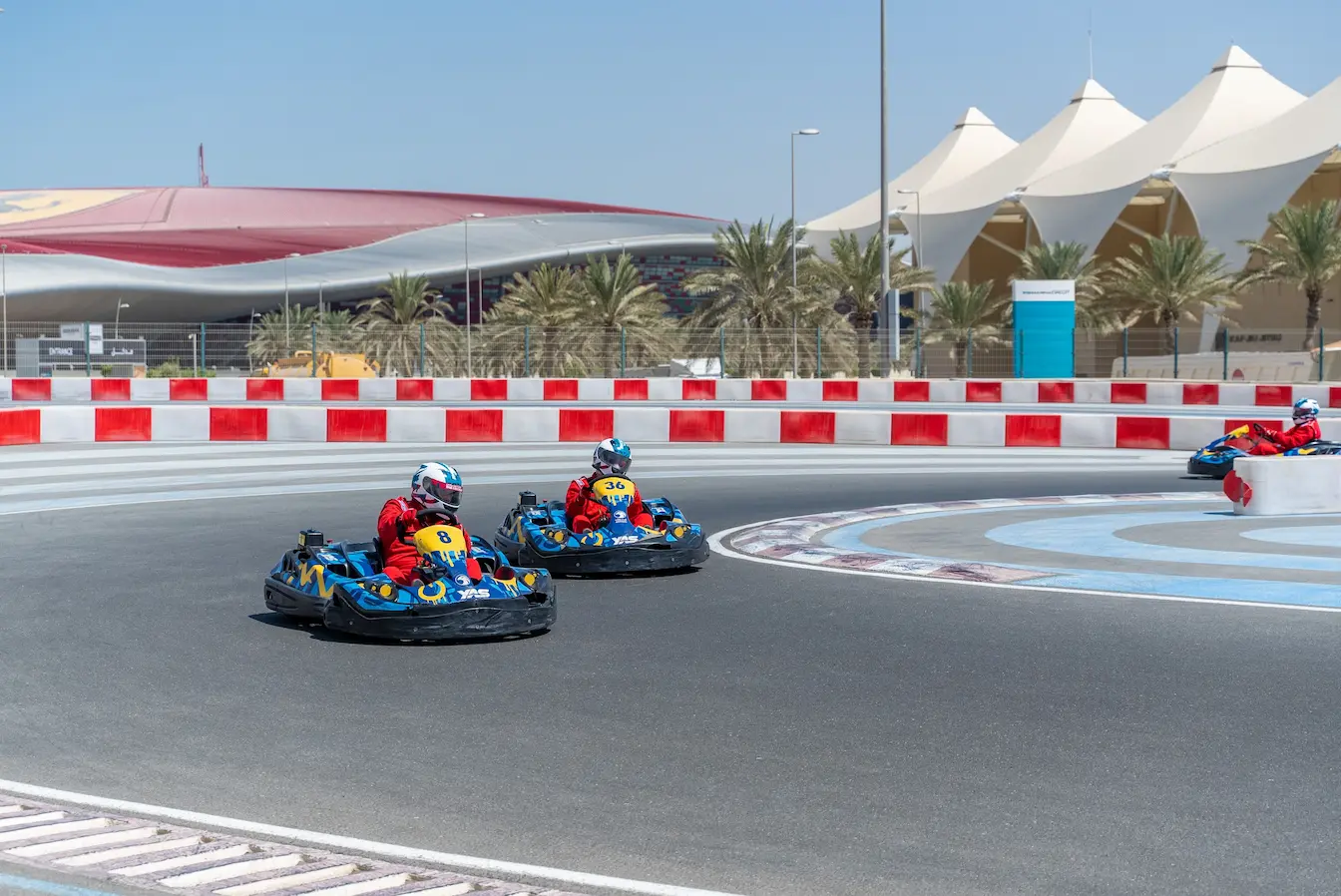 Trois pilotes en combinaison rouge sur karts bleus lancés sur piste, image qui illustre le circuit automobile le plus rapide du monde.