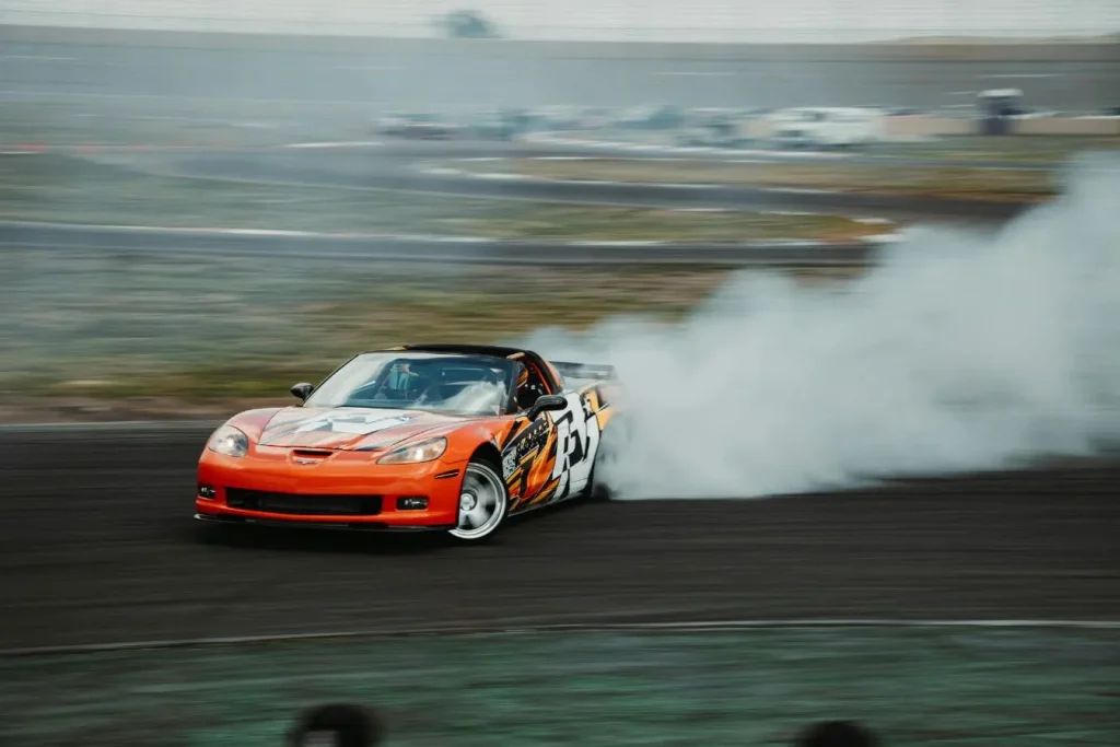 Bolide sportif orange produisant fumée blanche épaisse, image claire illustrant la technique du drift automobile.