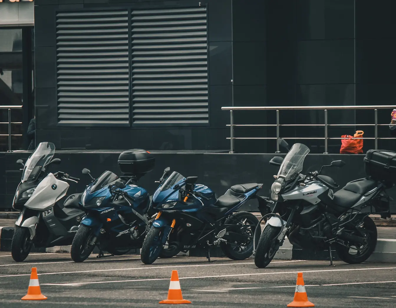 Cinq motos alignées sur sol pavé avec cônes orange, image qui illustre la différence entre permis A1 et A2.