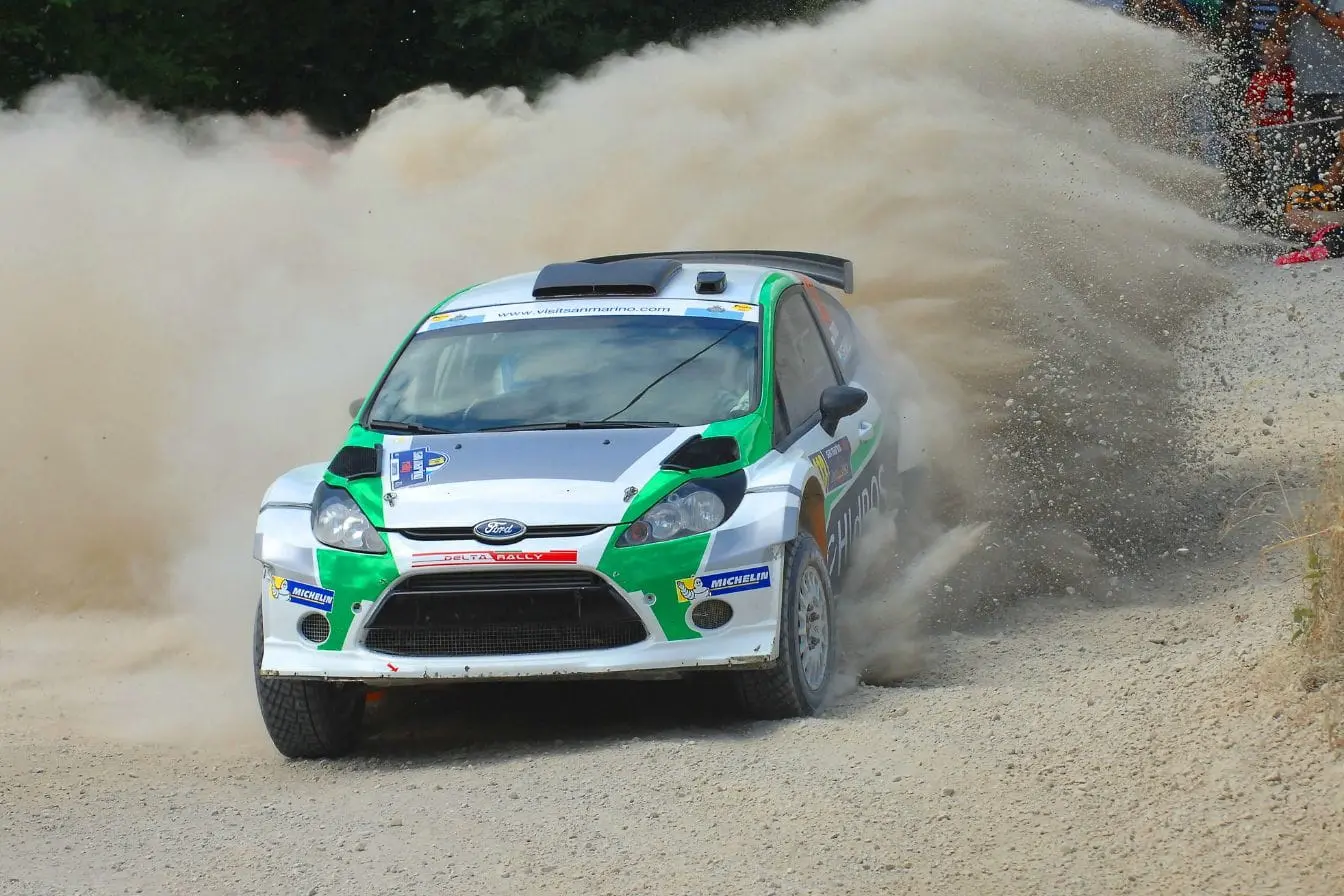 rallye Voiture de rallye Ford filant sur piste de gravier, reflet de l’intensité et des défis pour devenir pilote de rallye.