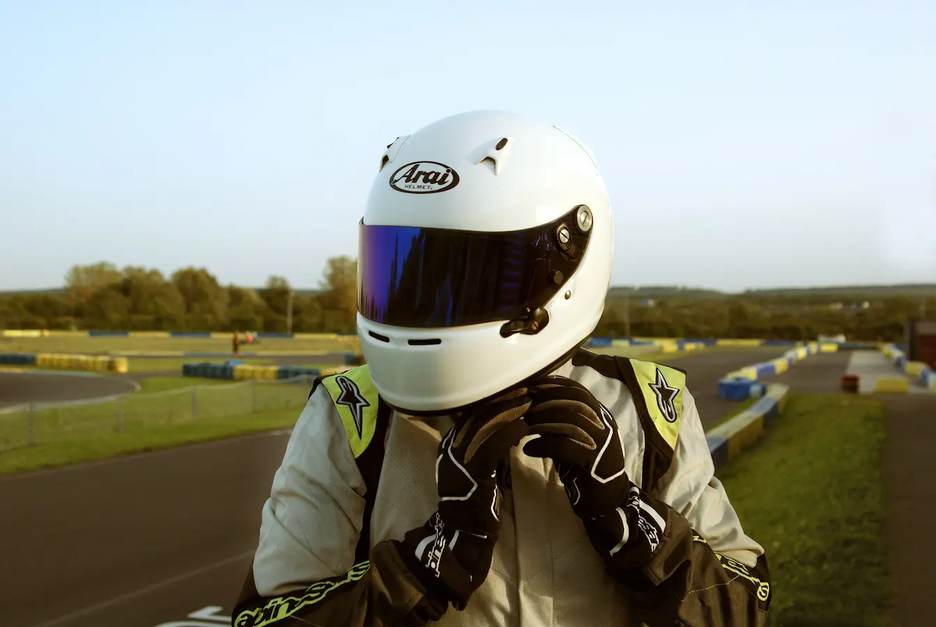 Pilote ajustant son casque blanc sur circuit, image d’un stage de pilotage où la sécurité et l’adrénaline se rencontrent.