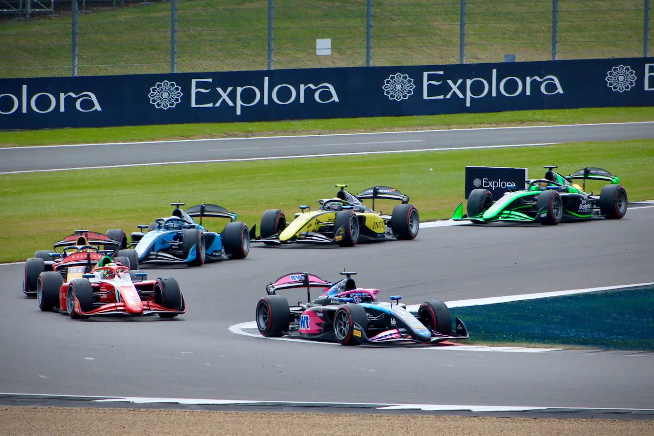 voitures de course Groupe de voitures de course colorées négociant un virage serré, reflet de l’intensité et de l’histoire des 24 Heures du Mans.