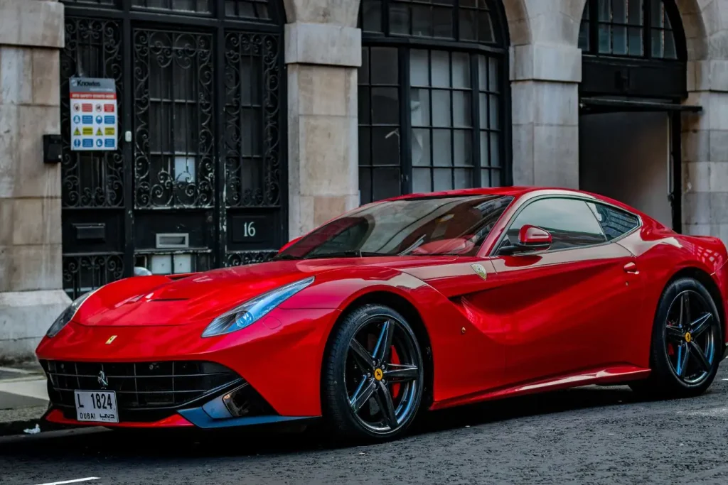 Ferrari rouge garée devant bâtiment en pierre, symbole de l’histoire d’une marque italienne iconique.